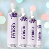 Four bottles of Wet's Hybrid Water + Silicone Blend Based Lubricant feature a hypoallergenic formula and come in varying sizes. The white bottles with purple caps and text are set against a bokeh background of colorful lights, emphasizing their premium silicone blend.